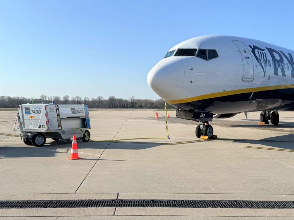 the itw gse 7400 battery driven ground power unit at the apron 2 meters from a ryan air aircraft with a blue sky in the background.